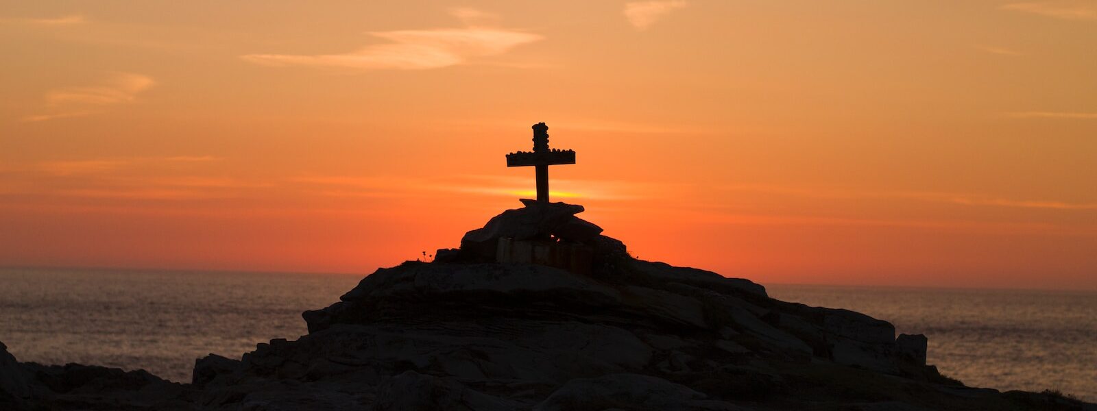 cross silhouette on mountain during golden hour