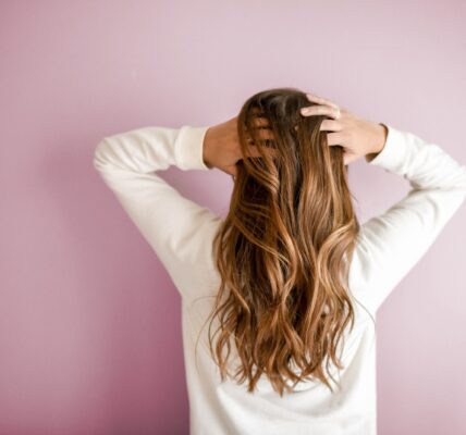 woman in white long-sleeved shirt standing in front of pink wall